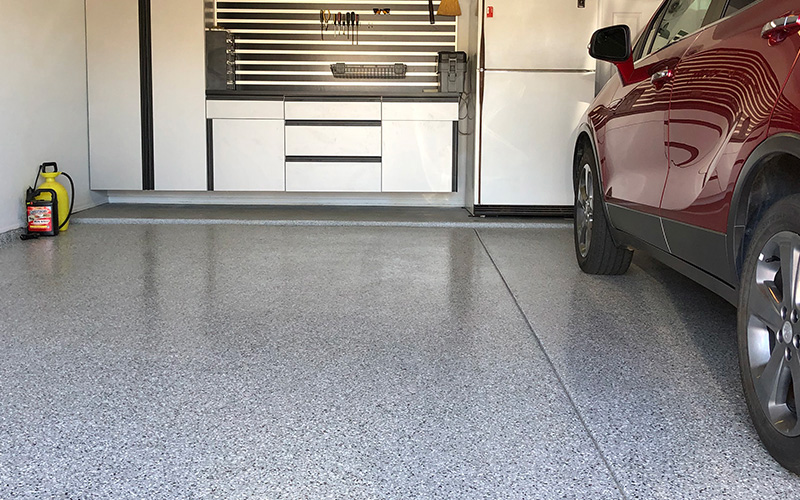 a garage with a red car parked on an epoxy floor.