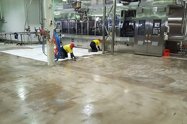 two workers clean epoxy floor in factory ensuring spotless and safe environment